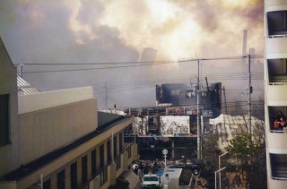 【長田区では倒壊とともに火災も発生した】煙の向こうに傾いた建物も見える。